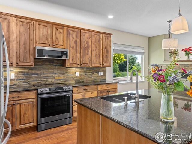 603 Summer Hawk Dr, Longmont, CO 80504 - kitchen with appliances with stainless steel finishes, a sink, brown cabinets, dark stone countertops, and recessed lighting