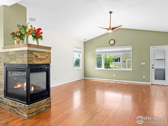 603 Summer Hawk Dr, Longmont, CO 80504 - unfurnished living room with wood finished floors, a stone fireplace, vaulted ceiling, ceiling fan, and baseboards