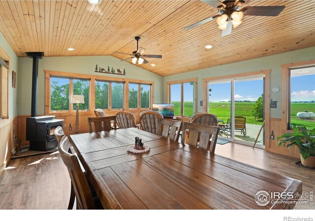 32924 County Road 29, Greeley, CO 80631 - dining space with wainscoting, a wood stove, vaulted ceiling, ceiling fan, and healthy amount of natural light