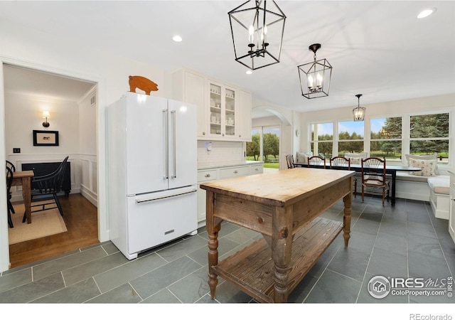 7215 Hygiene Rd, Longmont, CO 80503 - kitchen with freestanding refrigerator, a chandelier, glass insert cabinets, white cabinetry, and hanging light fixtures