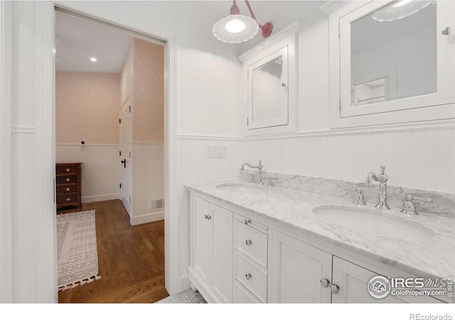 7215 Hygiene Rd, Longmont, CO 80503 - bathroom with double vanity, wood finished floors, and a wainscoted wall