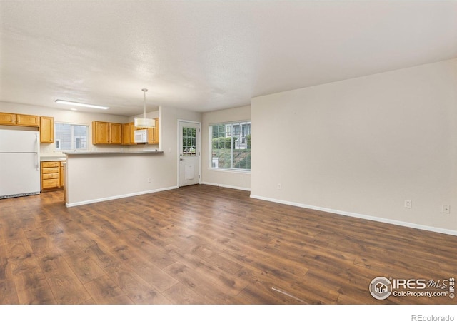 3660 W 25th St Unit 1106, Greeley, CO 80634 - unfurnished living room featuring dark wood-type flooring and baseboards