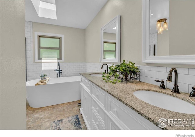 11290 Ranch Pl, Denver, CO 80234 - bathroom with healthy amount of natural light, tile walls, a skylight, double vanity, and a freestanding tub