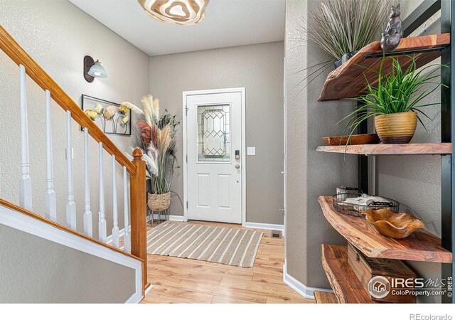 264 Alder Ave, Johnstown, CO 80534 - foyer entrance featuring wood finished floors, a textured wall, stairs, and baseboards