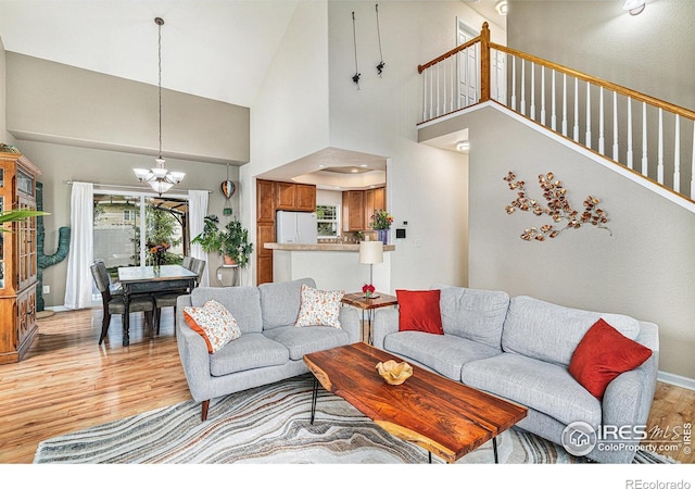264 Alder Ave, Johnstown, CO 80534 - living room with light wood finished floors, a chandelier, high vaulted ceiling, baseboards, and stairway