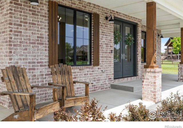 37179 Soaring Eagle Cir, Severance, CO 80550 - view of exterior entry featuring french doors, a porch, and brick siding