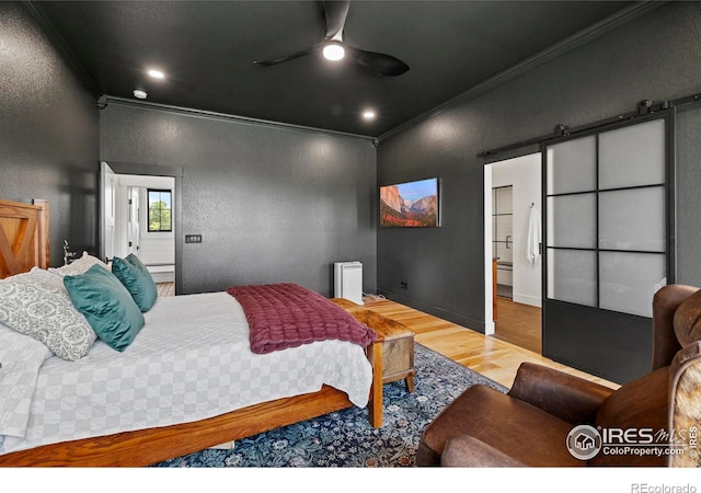 37179 Soaring Eagle Cir, Severance, CO 80550 - bedroom with ornamental molding, wood finished floors, a barn door, a textured wall, and a ceiling fan