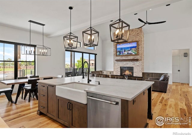 37179 Soaring Eagle Cir, Severance, CO 80550 - kitchen with stainless steel dishwasher, a sink, a chandelier, a brick fireplace, and high vaulted ceiling