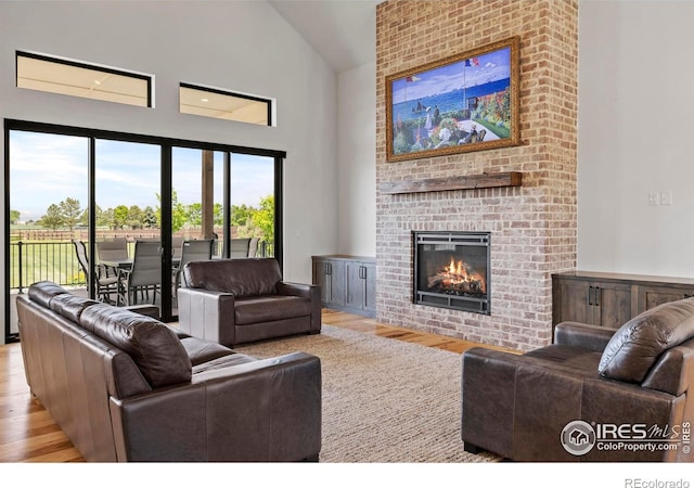 37179 Soaring Eagle Cir, Severance, CO 80550 - living area with high vaulted ceiling, wood finished floors, and a brick fireplace