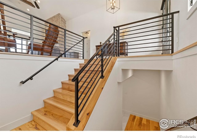 37179 Soaring Eagle Cir, Severance, CO 80550 - stairs featuring baseboards, a towering ceiling, wood finished floors, and a chandelier