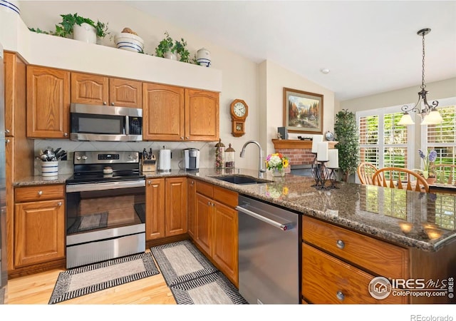 1142 Muirfield Way, Fort Collins, CO 80525 - kitchen with appliances with stainless steel finishes, a sink, vaulted ceiling, light wood finished floors, and brown cabinetry