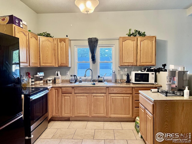 541 S Phelan Ave, Holyoke, CO 80734 - kitchen with black refrigerator, white microwave, stainless steel electric range oven, light countertops, and light tile patterned floors