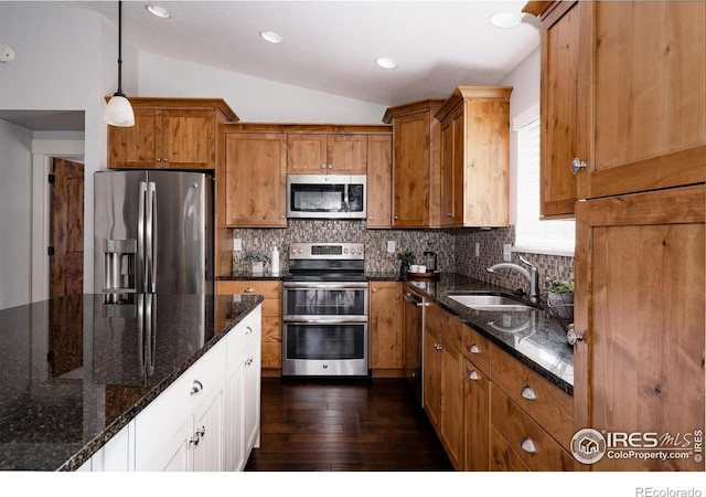 455 Radiant Dr, Loveland, CO 80538 - kitchen with appliances with stainless steel finishes, a sink, vaulted ceiling, decorative backsplash, and brown cabinets