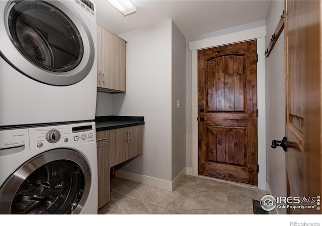 455 Radiant Dr, Loveland, CO 80538 - washroom with stacked washer and clothes dryer, cabinet space, baseboards, and a barn door