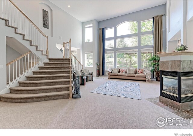 7858 Oban Ct, Lone Tree, CO 80124 - living area with a high ceiling, carpet flooring, stairway, a tiled fireplace, and recessed lighting
