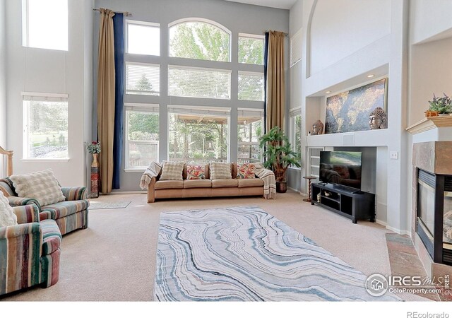 7858 Oban Ct, Lone Tree, CO 80124 - carpeted living area with a high ceiling, a tiled fireplace, healthy amount of natural light, and baseboards