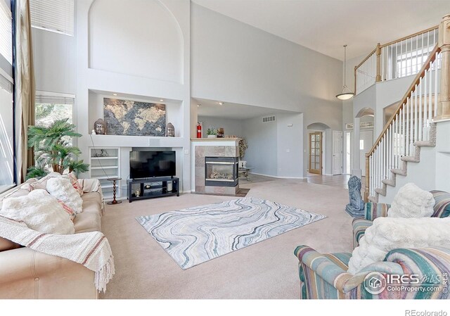 7858 Oban Ct, Lone Tree, CO 80124 - carpeted living room with a towering ceiling, arched walkways, stairway, a fireplace, and baseboards