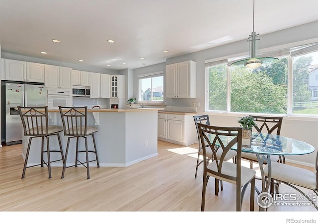7858 Oban Ct, Lone Tree, CO 80124 - kitchen featuring stainless steel appliances, light wood finished floors, white cabinetry, a kitchen island, and a breakfast bar