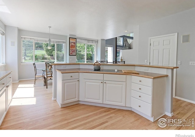 7858 Oban Ct, Lone Tree, CO 80124 - kitchen with light wood-type flooring, white cabinets, baseboards, light countertops, and decorative light fixtures