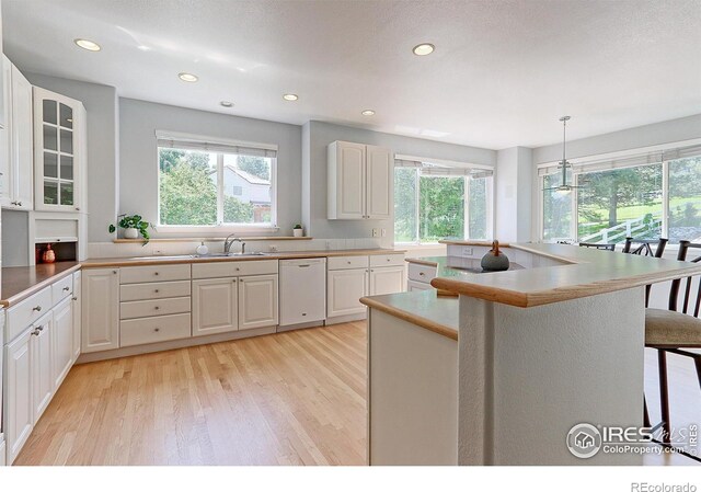 7858 Oban Ct, Lone Tree, CO 80124 - kitchen with dishwasher, plenty of natural light, light wood-style flooring, white cabinetry, and recessed lighting