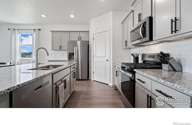 4709 Lynxes Way, Johnstown, CO 80534 - kitchen with stainless steel appliances, a sink, dark wood finished floors, gray cabinets, and backsplash