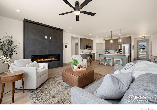 5016 Prairie Lark Ln, Severance, CO 80615 - living room with light wood finished floors, ceiling fan, a tiled fireplace, and recessed lighting