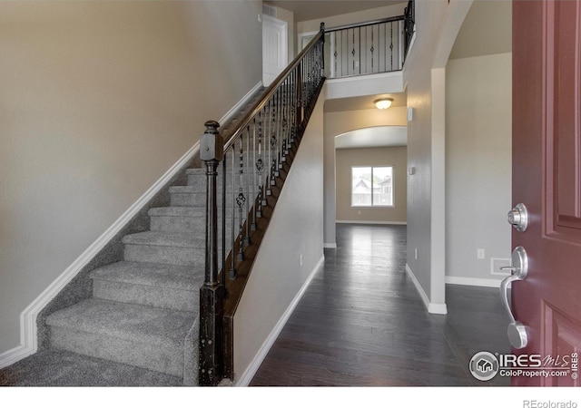 13598 Horseshoe Cir, Mead, CO 80542 - stairway with arched walkways, wood finished floors, and baseboards