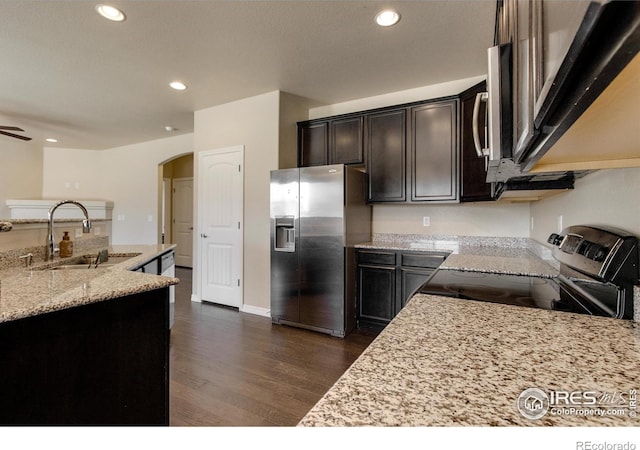 13598 Horseshoe Cir, Mead, CO 80542 - kitchen featuring stainless steel appliances, a sink, arched walkways, dark wood-style flooring, and light stone counters
