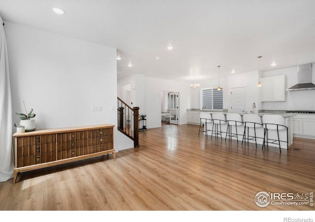 2031 Moon Rise Dr, Windsor, CO 80550 - unfurnished living room featuring light wood-style floors, recessed lighting, stairway, a chandelier, and a sink