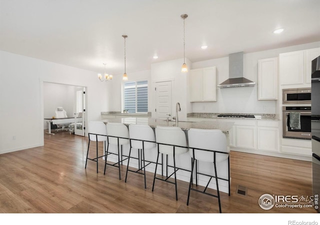 2031 Moon Rise Dr, Windsor, CO 80550 - kitchen with stainless steel appliances, wall chimney range hood, white cabinets, a chandelier, and a sink