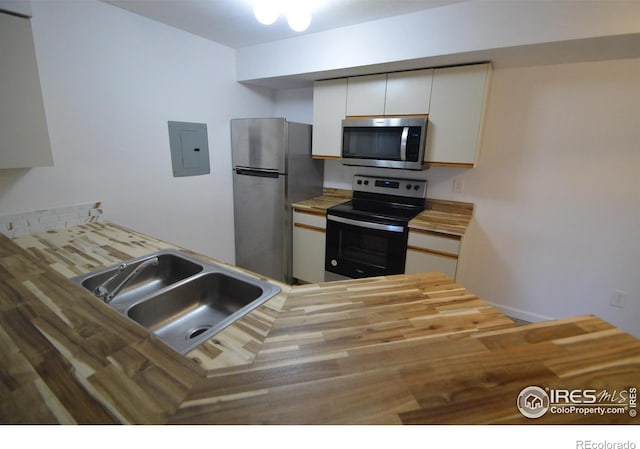 30 S Boulder Cir Unit 30182102, Boulder, CO 80303 - kitchen with stainless steel appliances, wooden counters, a sink, electric panel, and white cabinets