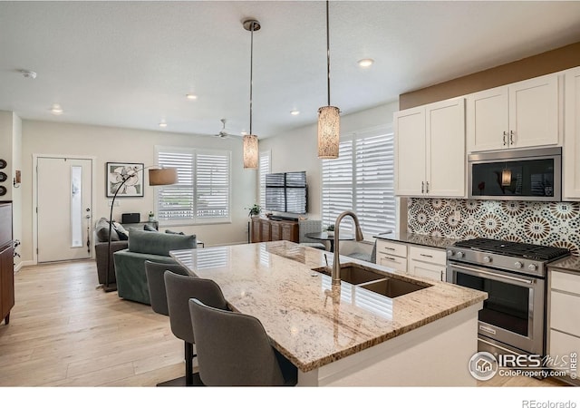 14553 W 91st Dr Unit A, Arvada, CO 80005 - kitchen with stainless steel appliances, a sink, plenty of natural light, white cabinets, and recessed lighting
