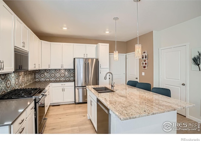 14553 W 91st Dr Unit A, Arvada, CO 80005 - kitchen featuring high quality appliances, a sink, light wood-type flooring, tasteful backsplash, and a center island with sink