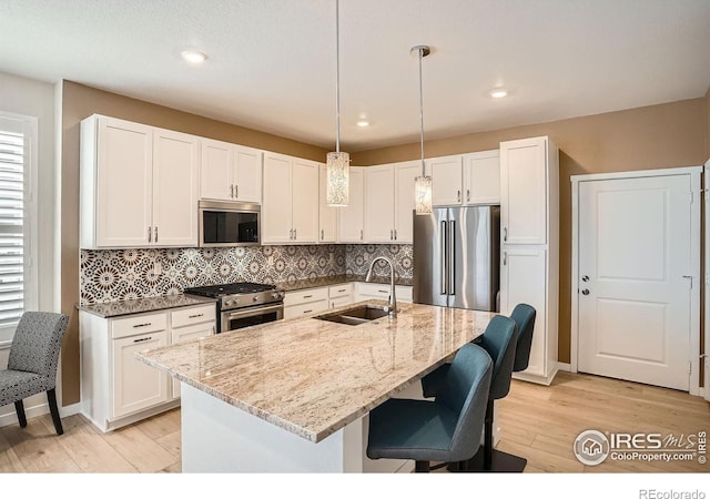 14553 W 91st Dr Unit A, Arvada, CO 80005 - kitchen featuring appliances with stainless steel finishes, a sink, light wood-style flooring, light stone countertops, and recessed lighting