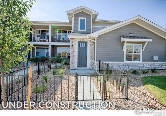 410 High Point Dr Unit 102, Longmont, CO 80504 - view of front of property featuring a gate, a fenced front yard, and stone siding