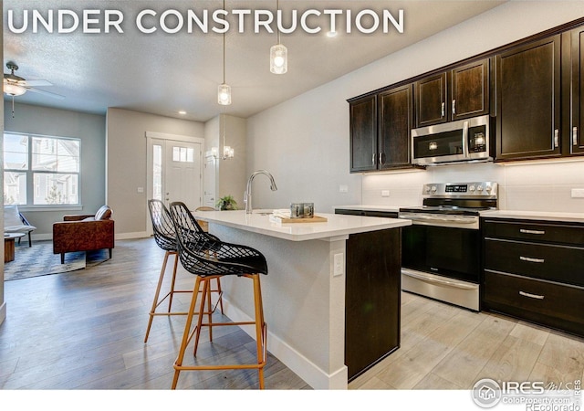 4173 Trapper Lake Dr, Loveland, CO 80538 - kitchen with stainless steel appliances, light wood-style flooring, light countertops, and a kitchen bar