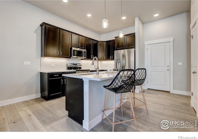 4173 Trapper Lake Dr, Loveland, CO 80538 - kitchen with stainless steel appliances, baseboards, light wood-type flooring, light countertops, and a center island with sink