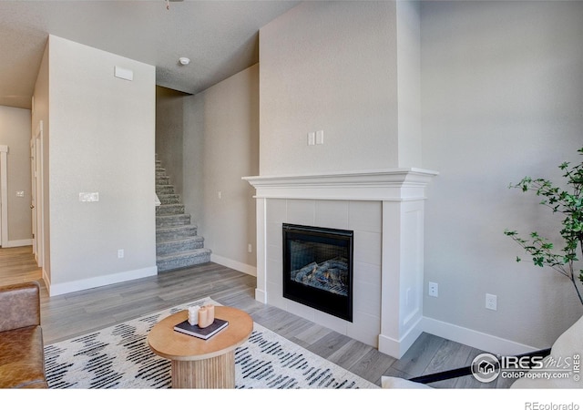 4173 Trapper Lake Dr, Loveland, CO 80538 - living area with wood finished floors, a tile fireplace, stairway, and baseboards
