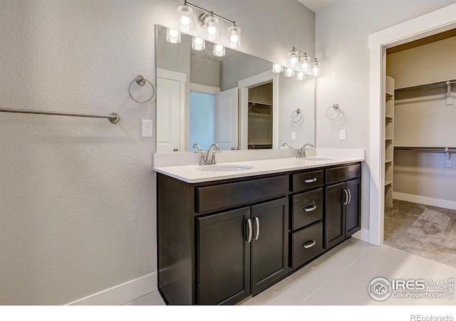 4173 Trapper Lake Dr, Loveland, CO 80538 - full bathroom featuring a spacious closet, double vanity, tile patterned floors, a textured wall, and baseboards