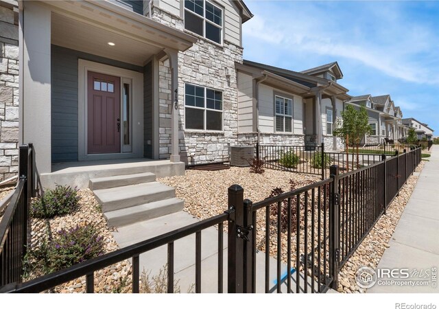 4173 Trapper Lake Dr, Loveland, CO 80538 - property entrance featuring stone siding, covered porch, a residential view, and a gate