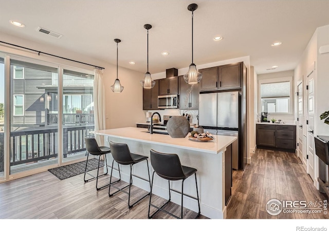2446 W 167th Ln, Broomfield, CO 80023 - kitchen featuring stainless steel appliances, light wood-type flooring, dark brown cabinets, light countertops, and a kitchen breakfast bar