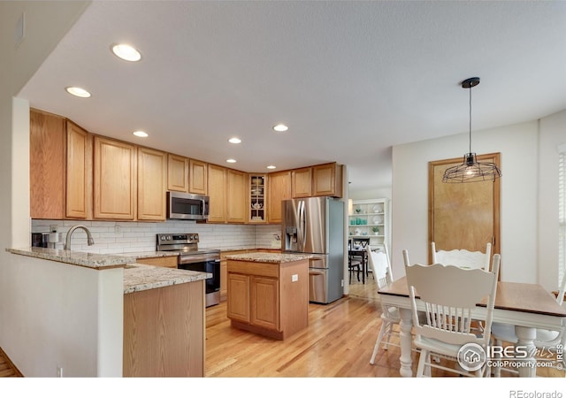 5603 Pierson Mountain Ave, Longmont, CO 80503 - kitchen with appliances with stainless steel finishes, light wood-style floors, glass insert cabinets, backsplash, and light stone counters