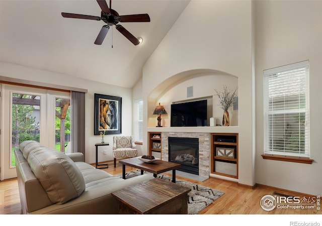5603 Pierson Mountain Ave, Longmont, CO 80503 - living area with high vaulted ceiling, a stone fireplace, ceiling fan, light wood-type flooring, and baseboards