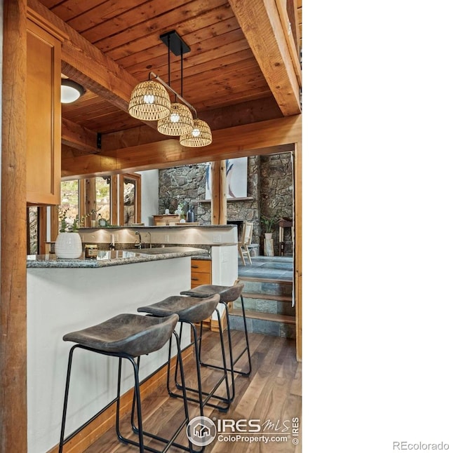 172 Tall Pine Ln, Boulder, CO 80302 - kitchen featuring wooden ceiling with exposed beams, light wood-style flooring, a peninsula, decorative light fixtures, and a fireplace