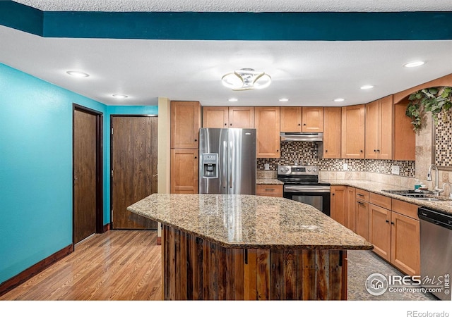 14000 E Linvale Pl Unit 210, Aurora, CO 80014 - kitchen with appliances with stainless steel finishes, under cabinet range hood, a sink, light wood-style floors, and light stone counters