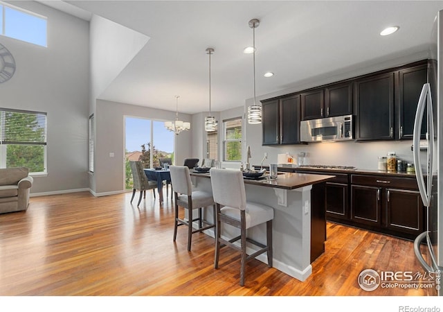 17805 Coral Burst St, Parker, CO 80134 - kitchen featuring stainless steel appliances, dark countertops, light wood-type flooring, a kitchen breakfast bar, and open floor plan