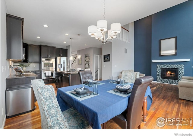 17805 Coral Burst St, Parker, CO 80134 - dining area with a chandelier, wood finished floors, a tiled fireplace, and recessed lighting