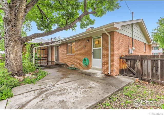 1025 Edinboro Dr, Boulder, CO 80305 - rear view of property featuring brick siding, a chimney, a patio, and a gate