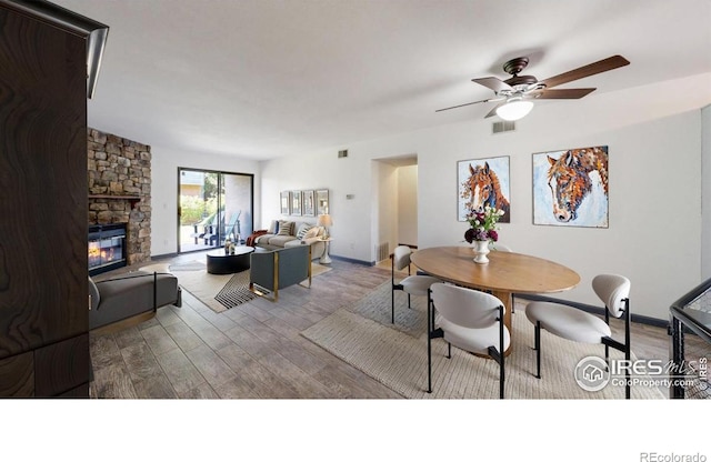 3526 S Depew St Unit 102, Lakewood, CO 80235 - dining room featuring wood finished floors, ceiling fan, a stone fireplace, and baseboards