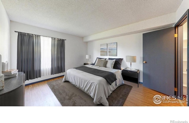 3526 S Depew St Unit 102, Lakewood, CO 80235 - bedroom with wood finished floors, a textured ceiling, and baseboard heating